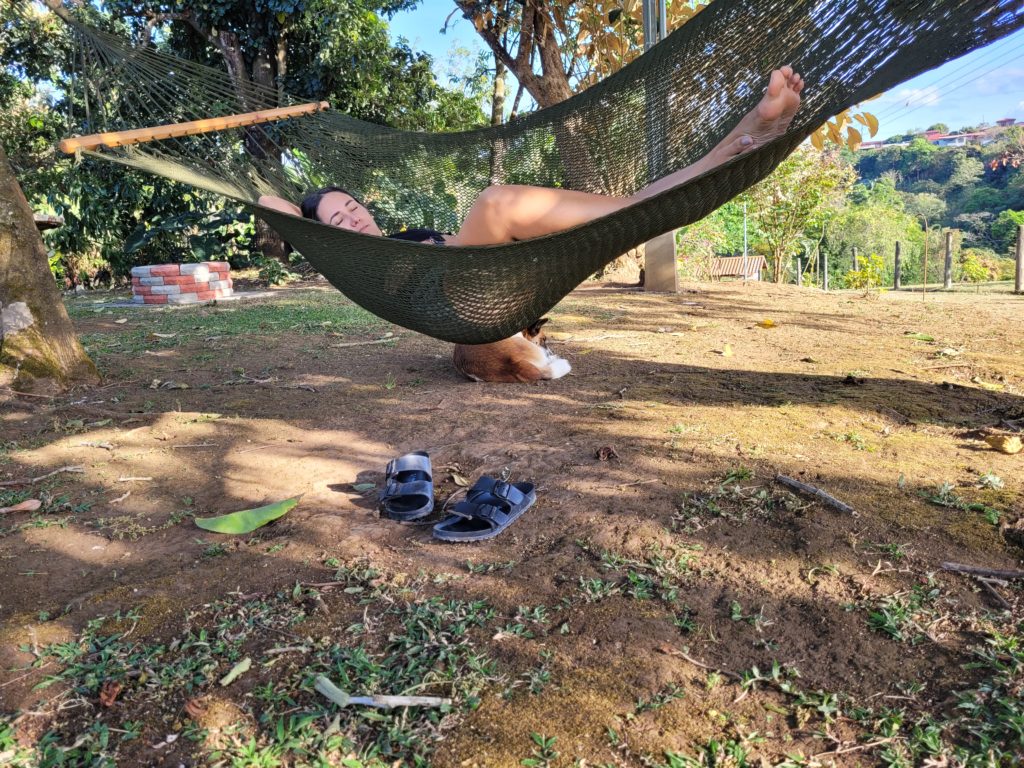 Adri lying in a hammock tied between two trees.